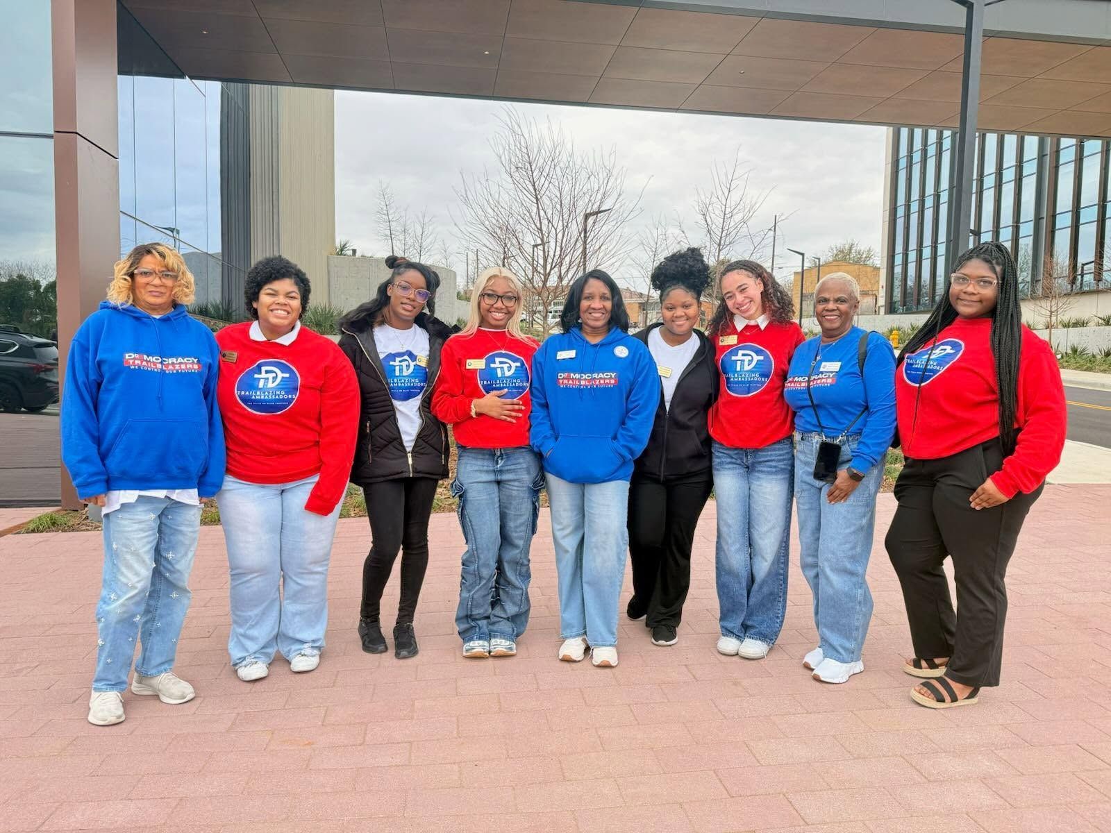 A line of students in red and blue Democracy Trailblazers hoodies