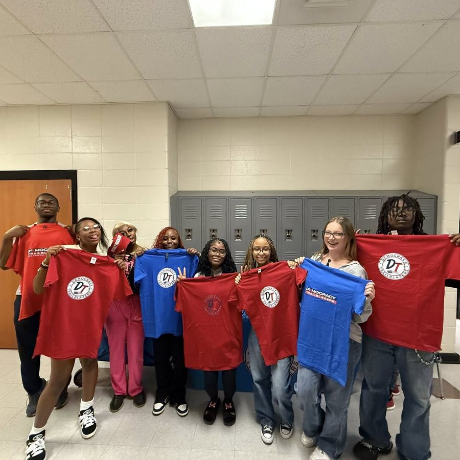 Students holding up red and blue Democracy Trailblazers shirts
